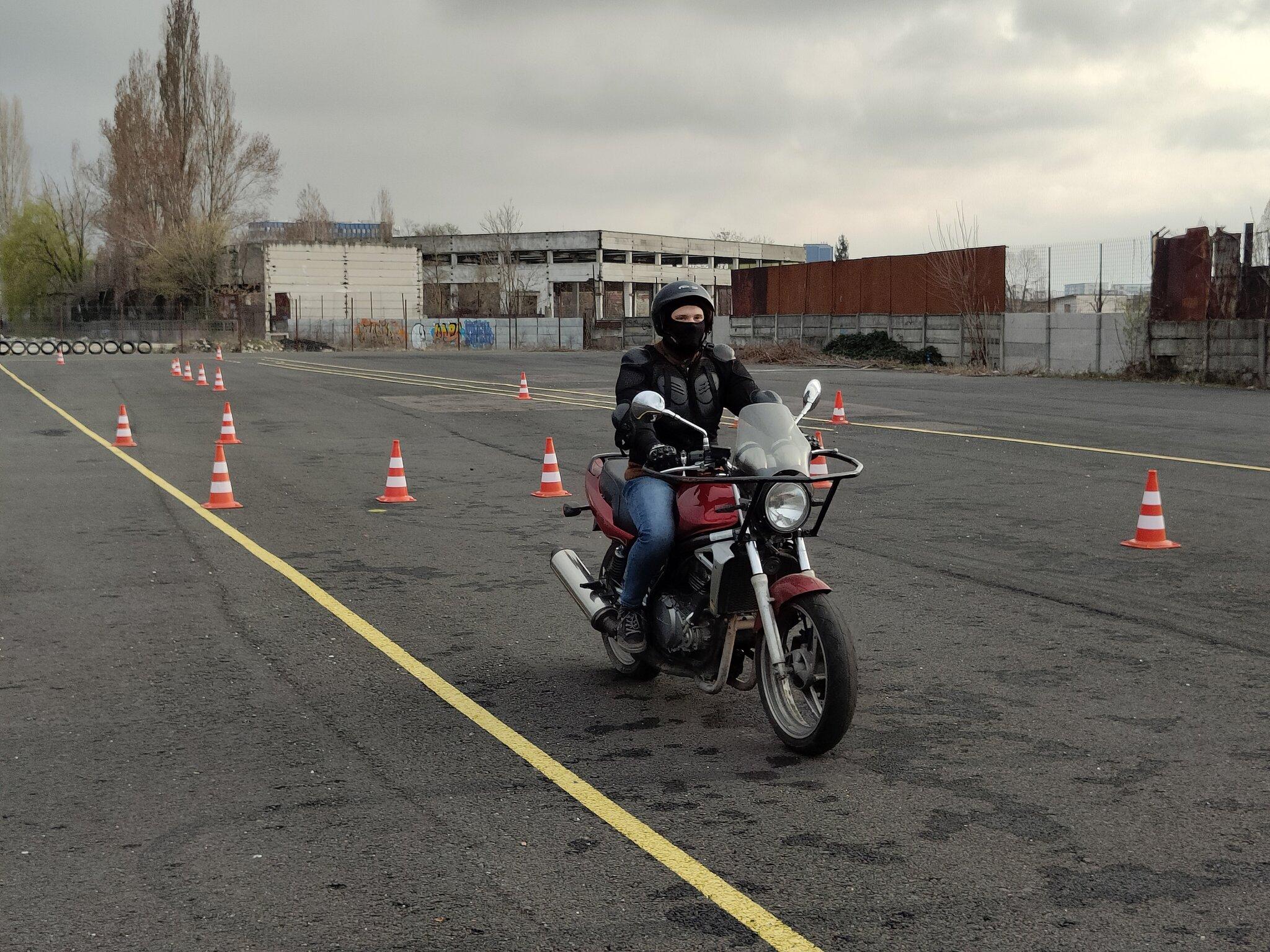 Motociclist exersând pe poligonul Școlii de Șoferi Giulești, cu conuri de ghidaj și marcaje vizibile